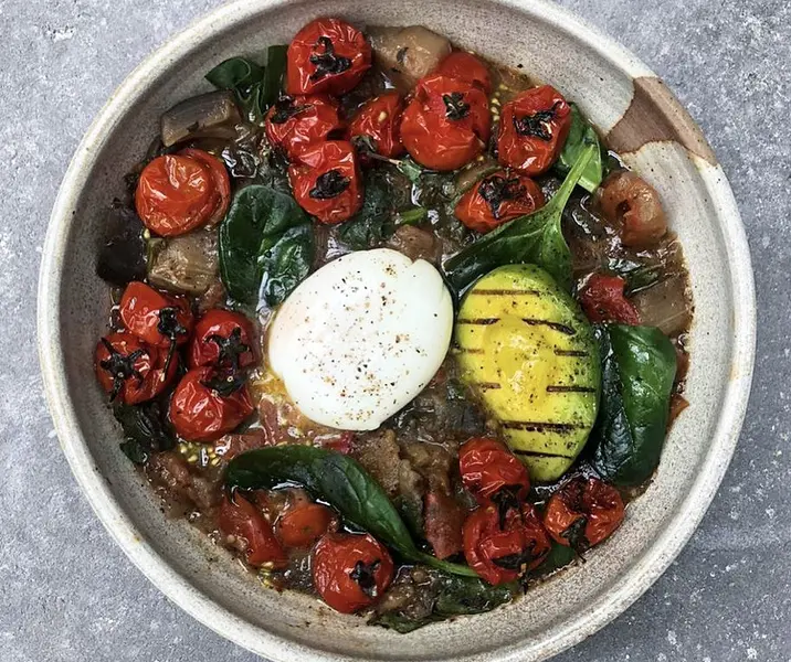Guiso de tomate, berenjena y espinaca, con huevo pochado y palta grillada