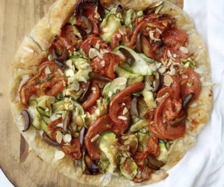 Tarta de tomate asado, queso de cabra, zapallo italiano y aceitunas