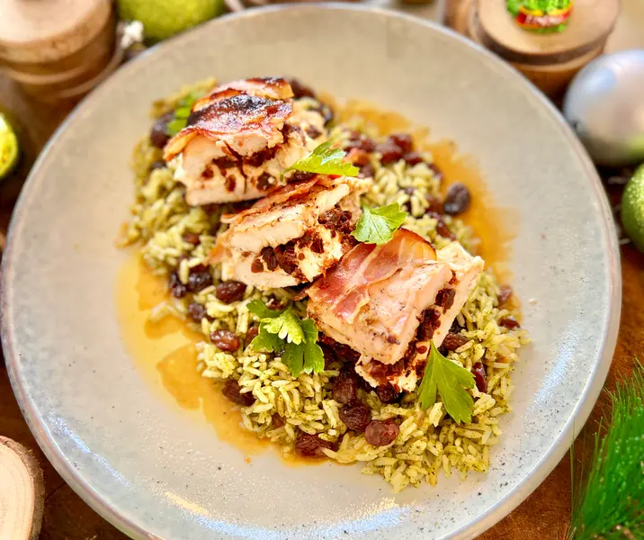 Pavo jugoso envuelto en tocino con arroz verde con pasas