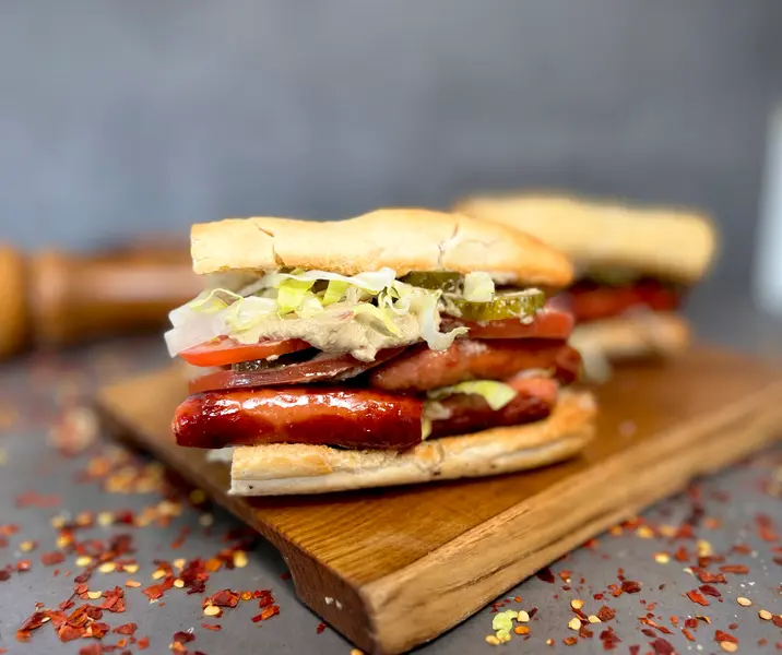 Sándwich de longanicilla al merkén con baba ganoush, tomate, lechuga y pepinillo