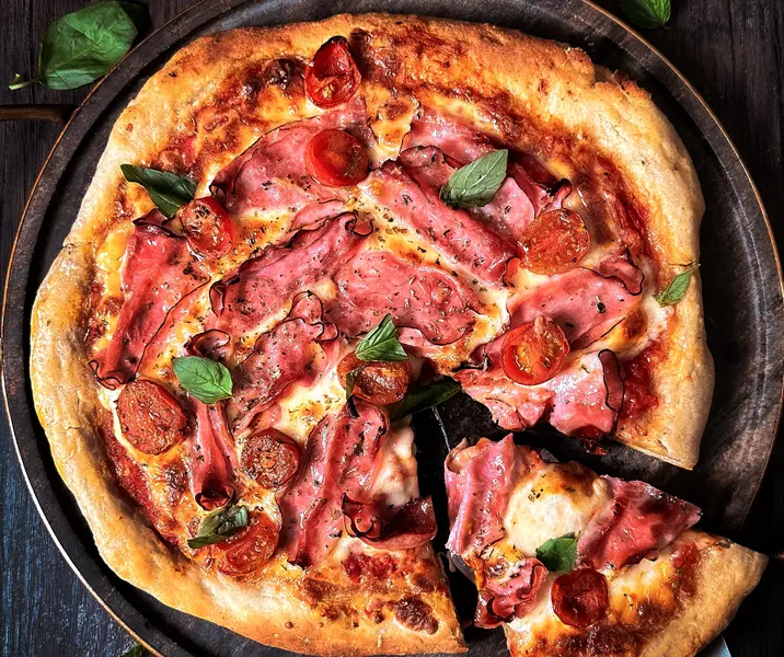 Pizzas caseras con jamón pierna, mozzarella, tomate y albahaca